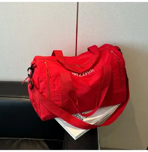 Vue détaillée d'un sac de voyage rouge avec tissu imperméable résistant et poignées robustes.