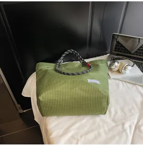 Detailed view of green checkered nylon tote bag with durable climbing rope handles, casual style.