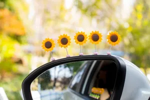 Close-up detail of cute shaking sunflower car mirror ornament, spring yellow flower decor for auto.