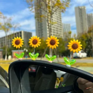 Close-up detail shot of cute sunflower dashboard bobblehead decorations mounted on car mirror.