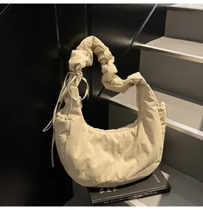 Closeup detail of the beige nylon cloud shoulder bag showcasing its unique pleated handle design.