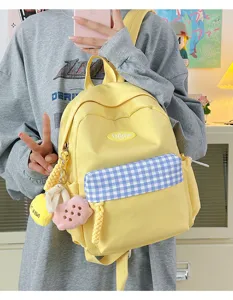 Yellow cute canvas backpack with blue plaid front pocket and sweet pendant for daily school use.