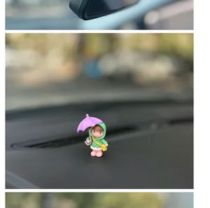 Close-up detail view of the cute cartoon umbrella girl car dashboard ornament in actual use.