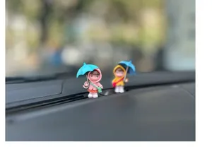 Cute cartoon umbrella girl car ornament detail shot, healing character dashboard decor item.