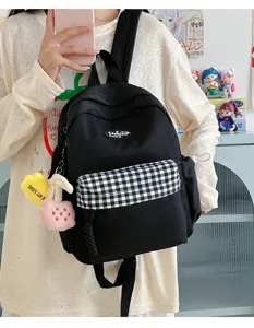 Detailed view of women's black mini backpack with plaid front pocket and cute charms.