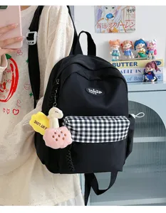 Casual black backpack for women, stylish minimalist school daypack with plaid front pocket and cute charms.
