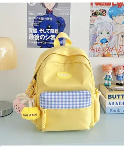 Yellow canvas mini backpack with blue plaid pocket and cute plush charm detail for daily use.