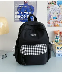 Black canvas backpack detail, featuring a classic plaid front pocket and sturdy top handle.