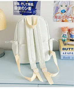 Detail shot of a minimalist white mini backpack on a desk, featuring adjustable canvas straps.
