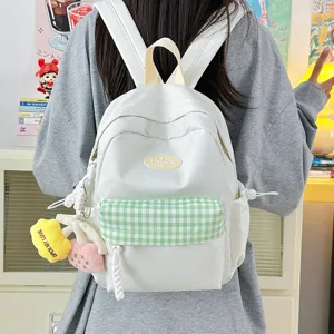 Cute white mini backpack with green plaid pocket and plush charms for women and teens.
