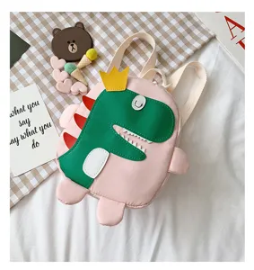 Detailansicht des niedlichen rosa Dino-Kinderrucksacks mit grünem Kronendesign und Riemen.