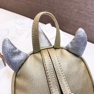 Close-up detail of children mini gold backpack with silver glitter horns and leather texture.
