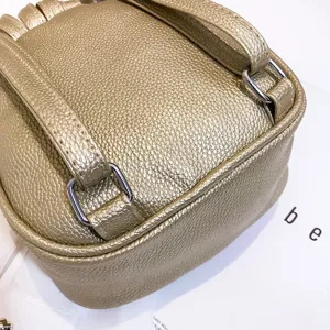 Gold metallic leather mini backpack detail showing shoulder strap and metal hardware.