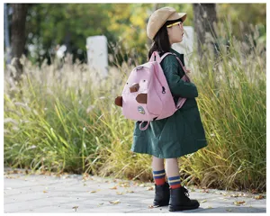 Cute pink corduroy children mini backpack outdoor detail scene with playful cartoon animal design.