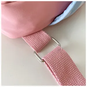 Kids chest bag strap detail, pink canvas webbing and silver metal square buckle close-up view.