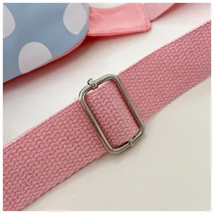 Close-up detail of children bag pink woven strap and metal adjuster buckle fashion item.