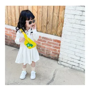 Cute kids yellow dinosaur crossbody bag with white dress outfit, ideal for casual daily wear.
