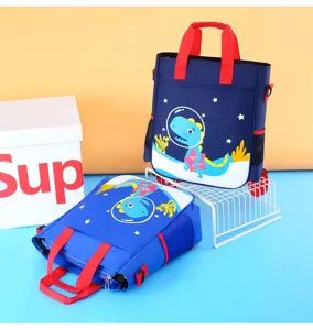 Detailed view of blue canvas kids tutoring bag with cute dinosaur astronaut print and red handles.