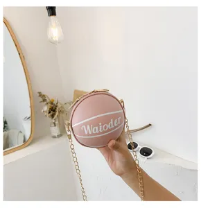 Pink round basketball shaped shoulder crossbody bag with gold chain strap for kids and women.