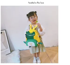 Detailed view of a cute cartoon dinosaur kids backpack worn by a child in a room setting.