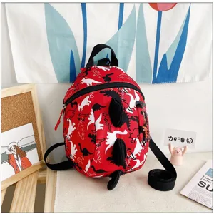 Close-up detail view of cute red cartoon dinosaur backpack with 3D spikes for kindergarten kids.
