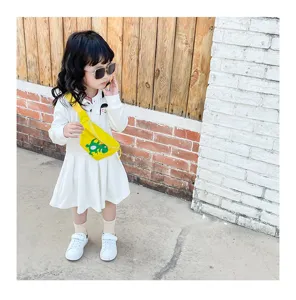 Close-up detail of a bright yellow kids crossbody bag featuring a cute cartoon dinosaur print.