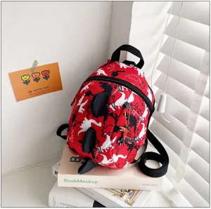 Detail shot of a red toddler dinosaur backpack with 3D spikes and cute pendant in a bright room.