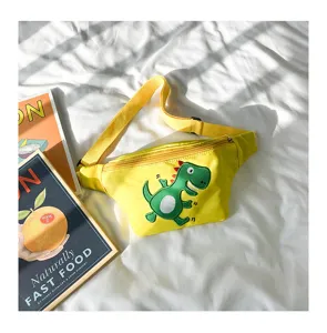 Cute yellow children waist bag with green cartoon dinosaur embroidery detail shot on white sheet.
