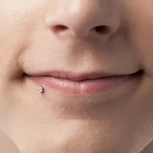 Close-up detailopname van 16G acryl lip piercing stud met sprankelende strass steen inleg.