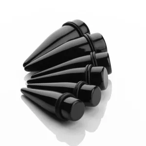 Close-up detail of black acrylic ear stretching tapers and plugs set with o-rings.