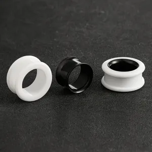 Vista detallada de elegantes joyas de piercing de expansion de oreja en negro y blanco.