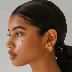 Close-up detail of a stylish gold organic sculpted ear stud and face dermal piercing.
