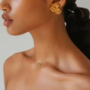 Detailed shot of exquisite minimalist gold floral earrings and cute bow dermal anchor top.