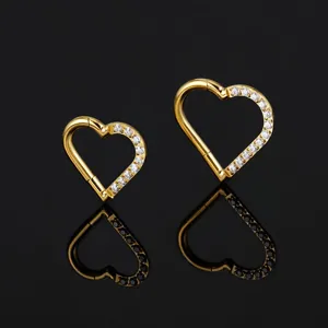 Nahaufnahme von goldenen Herz-Piercingringen mit funkelnden Zirkoniasteinen im Detail.