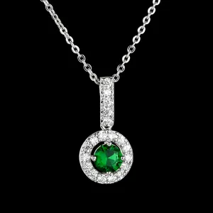 Detailopname van een zilverkleurige hangerketting met ronde groene steen en fonkelende zirkonrand.