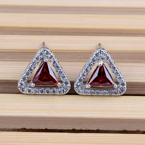 Primo piano dettagliato di orecchini geometrici in zircone, eleganti perle rosse e bianche.