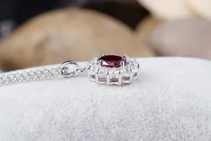 Detailaufnahme eines roten Zirkon-Anhaengers mit funkelnden Edelsteinen und edlem Halo-Design.