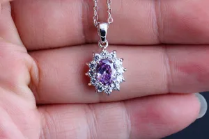 Elegante Silberkette mit einem ovalen lila Zirkonia umgeben von funkelnden klaren Steinen.