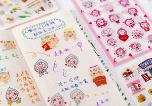 Detailed view of cute cartoon stickers pasted in a grid notebook for DIY journaling decoration.