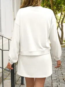 Detail view of a solid color long sleeve sweatshirt and skirt two-piece set in white.