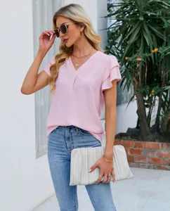 Vue détaillée d'un chemisier rose en mousseline à volants et col en V avec des jeans.