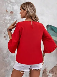 Back detail of a vibrant red women blouse with elegant ruffled bell sleeves and pearl button.