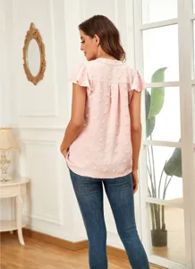 Detail view of the pink dot textured ruffle sleeve V-neck blouse paired with classic blue jeans.