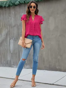 Detailed view of women's pink Swiss dot V-neck flutter sleeve blouse styled with blue jeans.