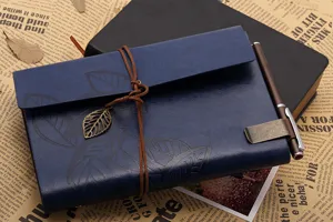Details of vintage blue leather journal notebook with leaf pendant and metal pen clip holder.