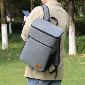 Detail shot of grey insulated picnic backpack worn outdoors in park setting showing strap design.