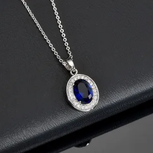 Detailed view of silver oval blue gemstone halo necklace with sparkling cubic zirconia stones.