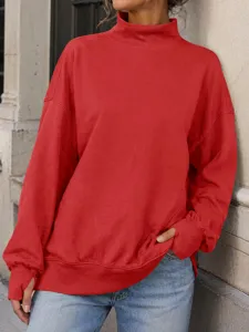 Primo piano di una felpa rossa oversize con collo alto, dettaglio streetwear casual.