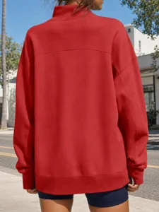 Dettaglio di felpa oversize rossa in tinta unita con collo alto e bordi a costine.