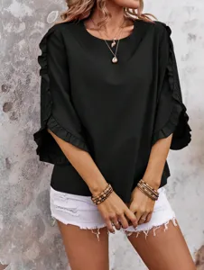 Detail view of black ruffle sleeve blouse with round neck, paired with white shorts.
